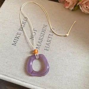 Detailed macro view of a vintage purple resin ring pendant necklace with an elegant cord.