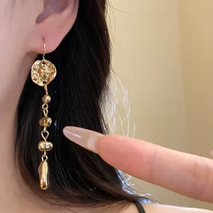 Vue détaillée de boucles d'oreilles pendantes dorées irrégulières portées par un mannequin