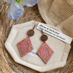 Détail de boucles d'oreilles bohèmes en bois avec imprimé floral sur pendentifs losange
