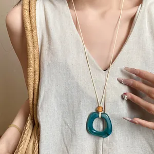 Elegant teal resin ring pendant necklace on cream cord, vintage geometric sweater chain.