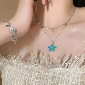 Detail view showing a starfish pendant necklace and shell bracelet on a model
