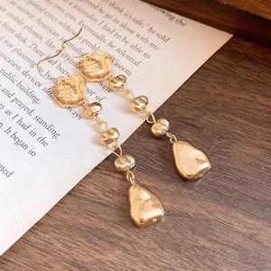 Gros plan de boucles d'oreilles dorées élégantes à texture martelée irrégulière sur livre