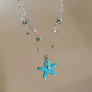 Detailed view of the blue enamel starfish pendant with green zircon charms on silver chain