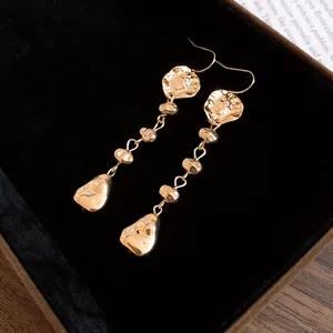 Vue détaillée de boucles d'oreilles pendantes dorées à effet froissé sur velours noir