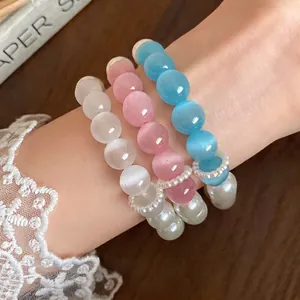 Set of three colorful cat eye stone and pearl beaded bracelets on wrist.