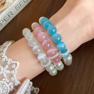 Close-up of colorful dopamine cat's eye stone and pearl beaded bracelets on a wrist