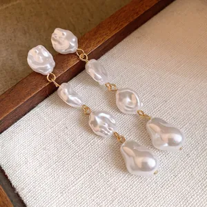Dettaglio di orecchini pendenti vintage con perle barocche irregolari e finitura oro