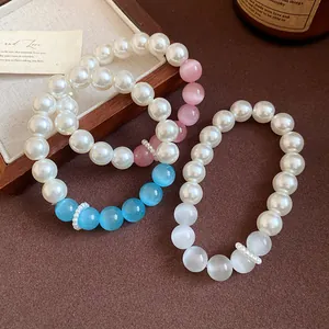 Close-up of cat eye stone and pearl beaded bracelets in blue, pink, and white tones