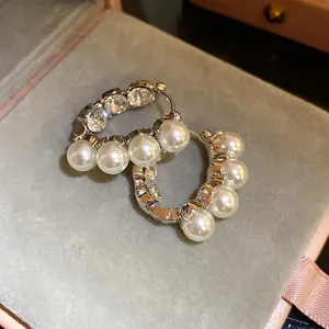 Dettaglio ravvicinato di orecchini a cerchio vintage francesi con strass e perle bianche
