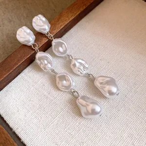 Primo piano di orecchini vintage con perle barocche e lunghe nappe stile