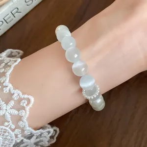 Detailed close-up showing texture of white cat-eye stone and pearl beaded bracelet
