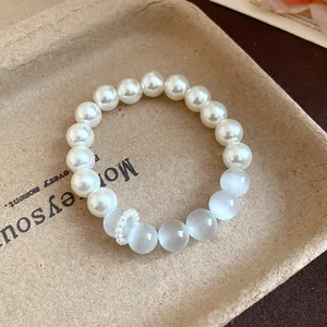 Detailed close-up showing white cat's eye stones and pearls on a rustic paper tray