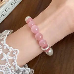 Elegant close-up shot of a pink cat eye stone and white pearl beaded bracelet on a wrist