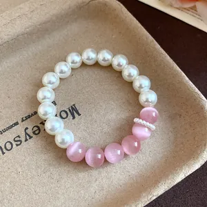 Macro detail of dopamine style pink cat's eye and white pearl beaded bracelet jewelry