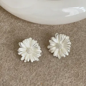 Dettaglio ravvicinato di eleganti orecchini a lobo a margherita in smalto bianco e argento.