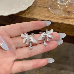 Gros plan de boucles d'oreilles fleurs en émail blanc avec pierres de zircone cubique.