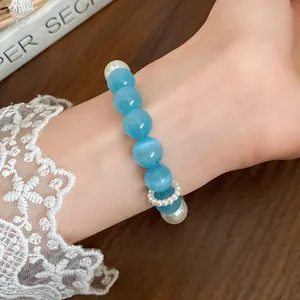 Detailed macro view of a blue cat eye stone and pearl beaded bracelet worn on wrist