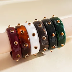Detail view of retro resin bangles featuring marble textures and gold-toned studded rivets