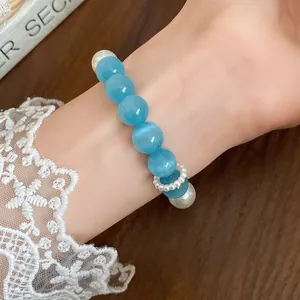 Close-up detail of a blue cat eye stone and pearl beaded bracelet worn on a wrist