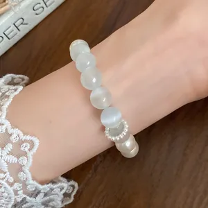 Detailed close-up view of an elegant cat's eye stone and pearl beaded bracelet on a wrist