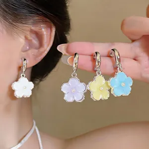 Detailed macro view of colorful resin flower dangle earrings with pearl centers worn on model