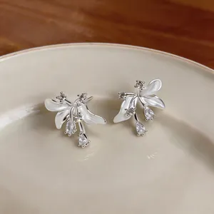 Vue détaillée de boucles d'oreilles fleurs en argent avec émail blanc et zircons.