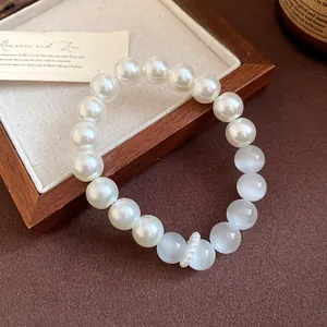 Detail of elegant bracelet featuring white pearls and cat's eye stones on a tray.