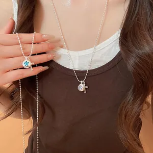 Detailed macro view of silver ball chain necklace with a star and cross charm pendant
