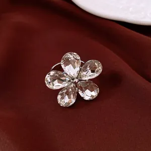 Gros plan d'une bague étincelante en forme de fleur avec cinq cristaux gouttes sur tissu rouge