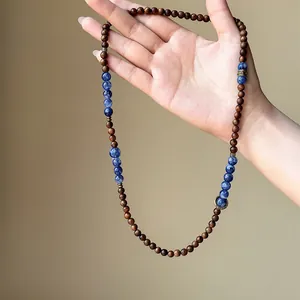 Close-up of retro wooden and blue stone beaded necklace held by hand showing texture