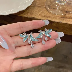 Gros plan détaillé de boucles d'oreilles fleur en émail bleu clair serties de zircon