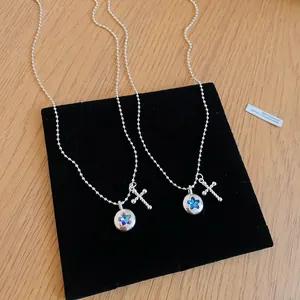 Detail shot of silver bead chain necklace with star and cross pendants on velvet pad