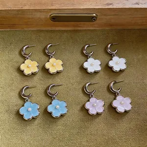 Close-up of sweet resin flower pendant earrings with pearl centers in four pastel summer colors