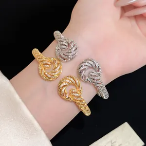 Detail shot of four luxury 18K gold plated twisted knot bangles with pavé zircons.