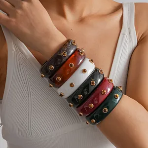 Detailed shot of vintage marbled resin bangles with gold rivets on a model's arm