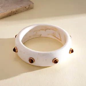 Detailed view of a vintage marbled resin bangle featuring amber-toned rivet studs