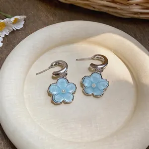 Detailed close-up showing light blue resin flower pendant earrings with pearl center.