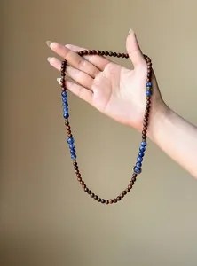 Macro shot of retro wooden and blue stone beaded necklace held by hand for detail