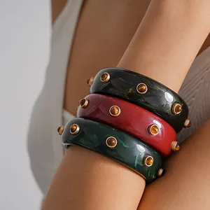 Detailed shot of resin marbled chunky bangles with amber-colored metal rivets.