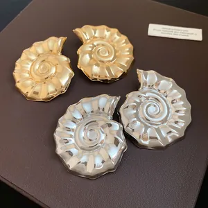Vista macro di orecchini a lobo a forma di nautilus in metallo lucido oro e argento