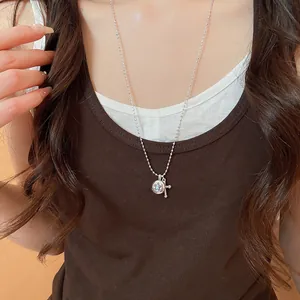 Close-up of silver-tone necklace with star-patterned stone and cross charms
