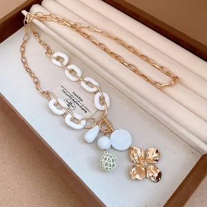 Detail of retro gold-tone necklace with flower pendant and white acrylic links.