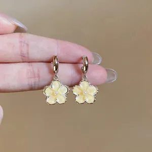 Detail view of sweet yellow resin flower drop earrings with elegant small pearl centers.