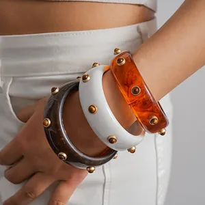 Close-up detail of vintage resin bangles featuring golden studs in amber and white