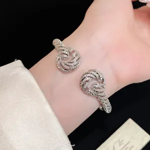 Close-up of a silver twisted zircon pavé open cuff bracelet worn on the wrist.
