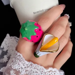 Vibrant Dopamine style strawberry and calla lily enamel rings worn on model's hand