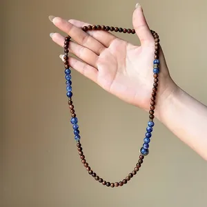 Detail showing texture of ethnic style wooden bead necklace with blue stone accents.