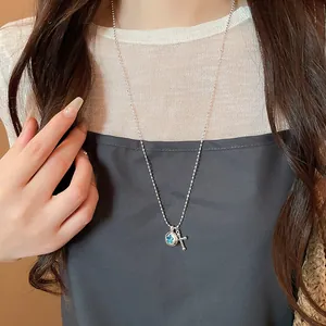 Detailed view of silver star and cross pendant necklace worn on model's neck.