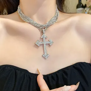 Detail view of a multi-layer rhinestone cross pendant necklace worn by a fashion model.