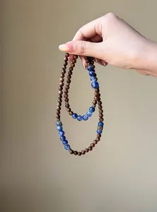 Close-up of retro wooden beaded bracelet with blue stone accents held by hand